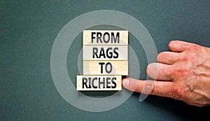 Rags or riches symbol. Concept words From rags to riches on wooden blocks. Beautiful grey table grey background. Businessman hand