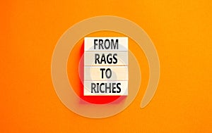 Rags or riches symbol. Concept words From rags to riches on wooden blocks. Beautiful orange table orange background. Business rags