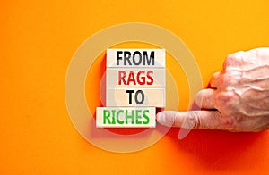 Rags or riches symbol. Concept words From rags to riches on wooden blocks. Beautiful orange table orange background. Businessman