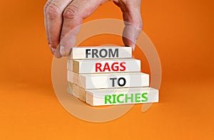 Rags or riches symbol. Concept words From rags to riches on wooden blocks. Beautiful orange table orange background. Businessman