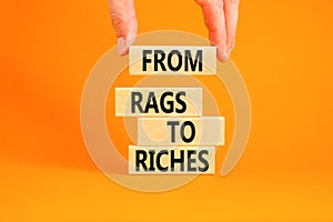 Rags or riches symbol. Concept words From rags to riches on wooden blocks. Beautiful orange table orange background. Businessman