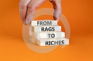 Rags or riches symbol. Concept words From rags to riches on wooden blocks. Beautiful orange table orange background. Businessman