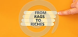 Rags or riches symbol. Concept words From rags to riches on wooden stick. Beautiful orange table orange background. Businessman