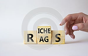 Rags vs Riches symbol. Businessman hand points at wooden cubes with words Rags and Riches. Beautiful white background. Rags vs