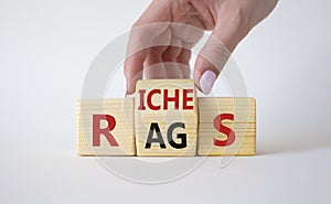 Rags vs Riches symbol. Businessman hand turns wooden cubes and changes the word Rags to Riches. Beautiful white background. Rags