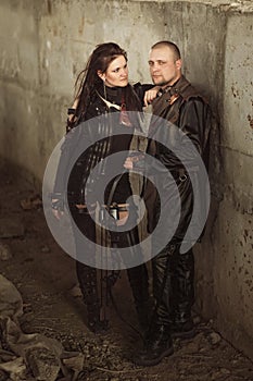 Raider man and woman in leather costume with a bow at post-apocalyptic world.