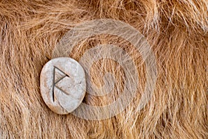 Raido or Raidho Nordic stone rune on animal fur. Letter Raed of the Viking alphabet photo
