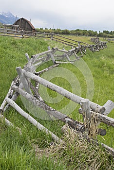A rail fence leads into an old historic barn.