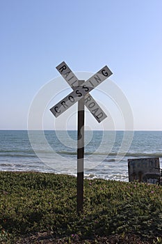 Rail Road Crossing Sign with Ocean and Blue Sky Background