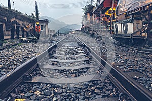 Rail track heading out from train station to foggy mountain, traveling theme, old time look