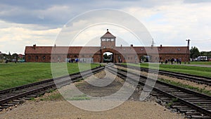 Rail tracks, gate house with guard tower in the background, of Auschwitz concentration camp