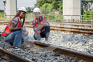 Rail transportation engineer in safety vest and hardhat check the neatness of the railway track while holding walkie-talkie and