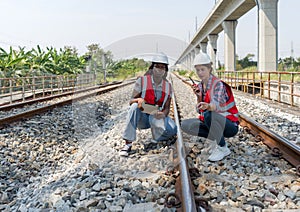 Rail transportation engineer in safety vest and hardhat check the neatness of the railway track while holding walkie-talkie and