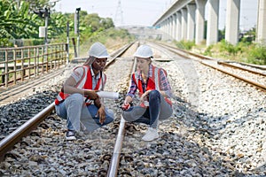 Rail transportation engineer in safety vest and hardhat check the neatness of the railway track while holding walkie-talkie and