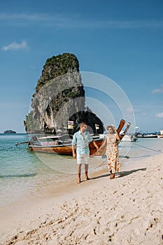 Railay Beach Krabi Thailand, couple walking in the morning on the beach with tropical cliffs and long tail boats on the