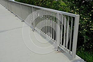 Railing at the bridge with vertical fence bars anchored to the ground with four concrete screws. plastic caps