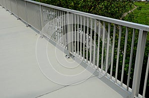 Railing at the bridge with vertical fence bars anchored to the ground with four concrete screws. plastic caps