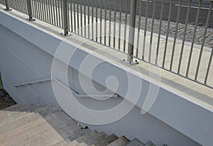 Railing at the bridge with vertical fence bars anchored to the ground with four concrete screws. plastic caps