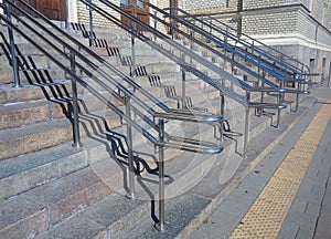 Railing shadows on steps of modern granite staircase. Light and shadow pattern