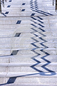 Railing shadows on steps of modern granite staircase