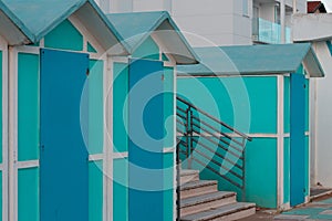 A railing of a staircase between blue beach shedsItaly, Europe