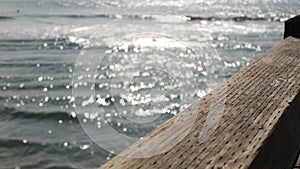 Railings of wooden pier, waterfront boardwalk, California beach USA. Defocused ocean, sea waves.