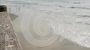 Railings of wooden pier, waterfront boardwalk, California beach USA. Defocused ocean, sea waves.