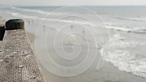 Railings of wooden pier, waterfront boardwalk, California beach USA. Defocused ocean, sea waves.