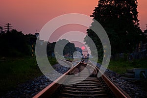 Railroad against beautiful sky at sunset. Industrial landscape with railway station, colorful gold sky, trees and grass, yellow