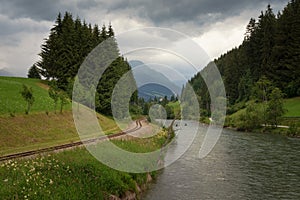 Railroad along the river Mur, Austria, stormy day, alpine landscape