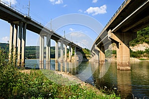 Railroad and automobile trestle bridges over Tsonevo dam, at Luda Kamchia river in Bulgaria against blue sky with clouds. Transpor