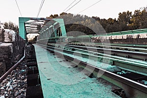 Railroad bridge with symmetrical metal structure and tracks. Turquoise Color