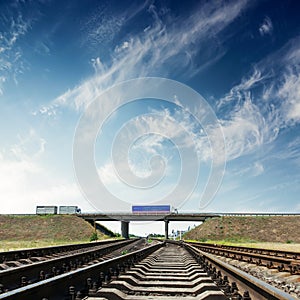 Railroad closeup and bridge with autos under blue sky