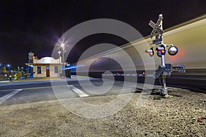 Railroad crossing with passing train by night