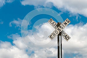 Railroad Crossing Sign Against Cloudy Sky