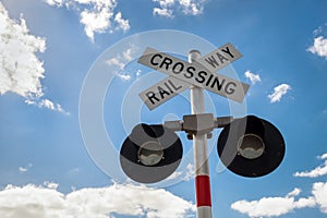 Railroad Crossing Sign with blue clear sky and white clouds. Railway crossing sign with flashing lights