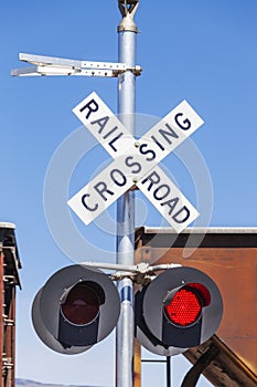 Railroad crossing sign and flashing red light with a passing freight train