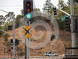 Railroad crossing sign on a track intersection on a busy street with hill