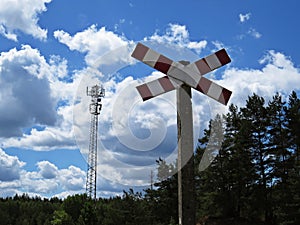 Railroad Crossing Warning Street Sign with Forest and Broadcasting Tower at Background