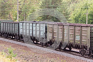Railroad and freight train with rusty railway wagons going along forest. Transportain, cargo concept