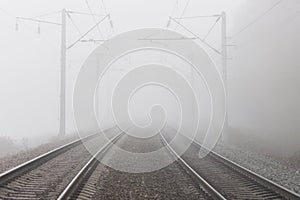 A railroad going into fog in the middle of an autumn landscape.