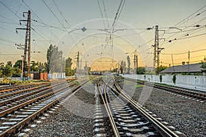 Railroad lines diverging in different directions at the station in the evening at sunset