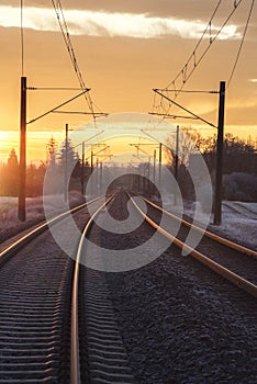 Railroad lines through rural scenery at sunrise