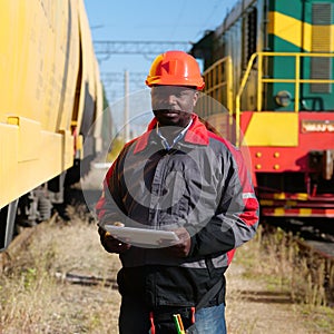 Railroad man in uniform and red hard hat with computer