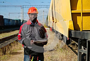 Railroad man in uniform and red hard hat with computer