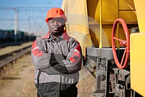 Railroad man in uniform and red hard hat look at the camera