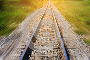 Railroad in motion with sun rays background. Blurred railway. Transportation.