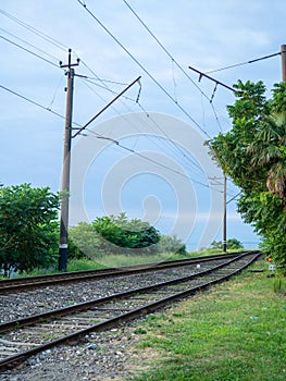 Railroad on the outskirts of the city. Road for electric transport among the trees. Sleepers and rails. Concept of path and