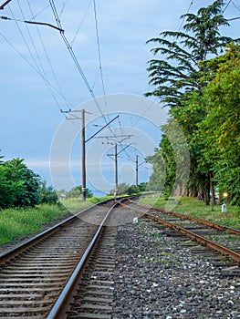 Railroad on the outskirts of the city. Road for electric transport among the trees. Sleepers and rails. Concept of path and