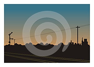 Railroad and rail signalling with trees and industrial area silhouette background.